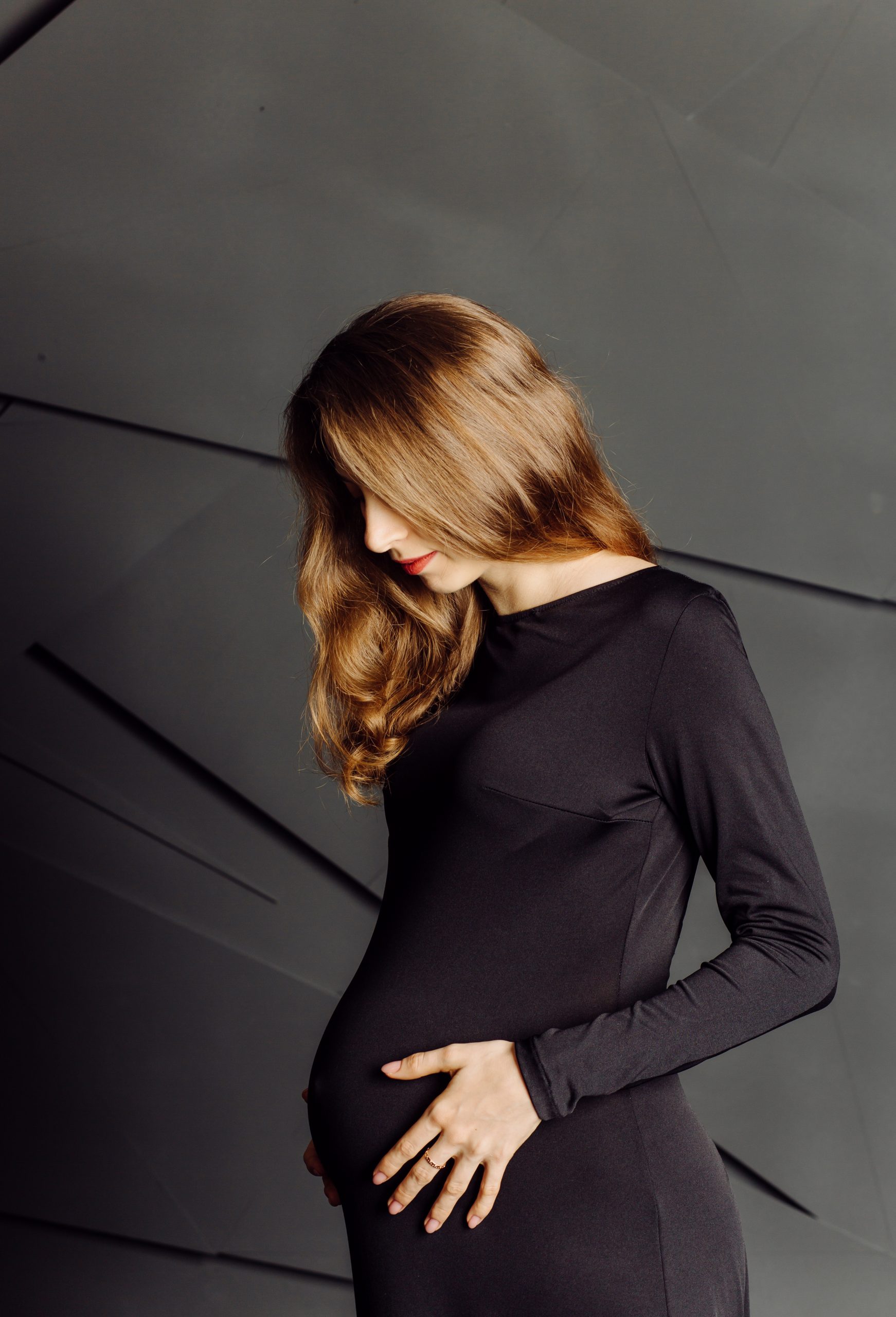 Young beautiful pregnant woman in black dress. Pregnancy fashion look concept